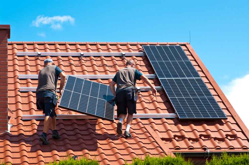 Two men installing new solar panels on the roof